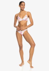 Bikini-set med blommönster som har en triangeltopp med tunna remmar och låg midja på byxorna, främst i pastellnyanser av rosa och vitt.
