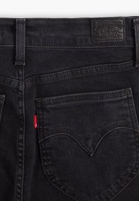 Sorte denim jeans med rett passform, med et signaturdesign på baklommen og rød merking. Teksturert stoff med synlige sømmer.