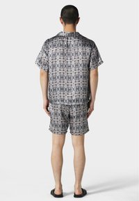 Kurzarmshirt und Shorts im grauen und schwarzen abstrakten Muster, aus leichten Stoff gefertigt, mit lockerer Passform und flachen Nähten.