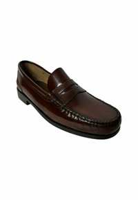 Mocasín de cuero marrón con un acabado suave, detalles de costura en la parte superior y un tacón bajo. Diseñado para facilitar su calzado.
