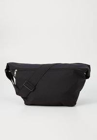 Bolsa de ombro de tecido preto com um design elegante, fecho superior com zíper, alça ajustável e uma textura suave. Compacta e funcional.
