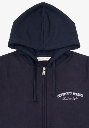 Sudadera con cremallera de color azul marino, hecha de un tejido suave. Presenta una gran capucha, cordones y el texto bordado "VARSITY TEAM" en el pecho.