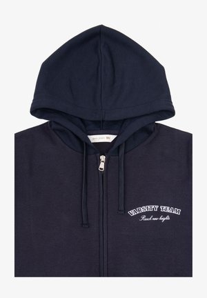 Felpa con zip di colore blu navy, realizzata in tessuto morbido. Presenta un grande cappuccio, lacci e testo ricamato "VARSITY TEAM" sul petto.