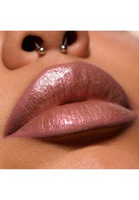 Glansende lyserøde læber med en skinnende finish; tæt på, hvor tekstur og detaljer fremhæves. En sølvfarvet hoop-næsering er synlig over læberne.