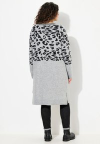 Lång grå cardigan med svart leopardmönster på övre ryggen, med ribbade ärmkanter och nederkant, samt sidofickor för ökad rörlighet.