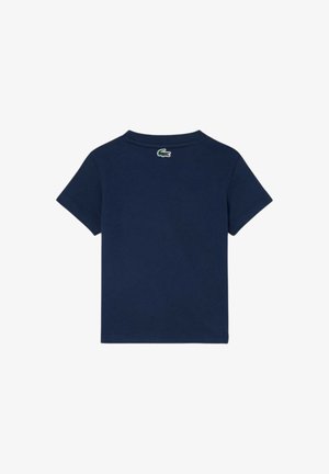 Maglietta a maniche corte blu navy con un piccolo logo coccodrillo verde e bianco posizionato centralmente sotto la nuca sul retro.