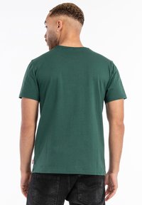 Grøn bomulds t-shirt med klassisk pasform og korte ærmer, med en rund halsudskæring og et lille mærke ved kanten.
