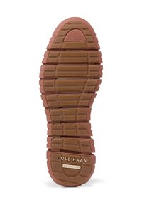 Suola in gomma marrone con superficie texturizzata, caratterizzata da scanalature orizzontali e creste. Marchio visibile: "Cole Haan GRAND. 360."