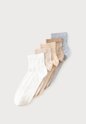 Cinq paires de chaussettes courtes en blanc, beige, marron clair, beige et gris, disposées en chevauchement sur un fond clair.