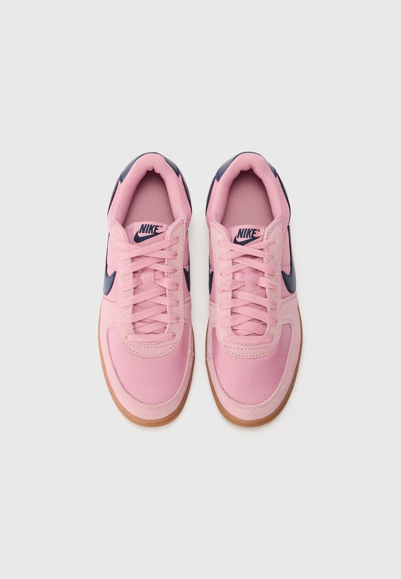 Baskets Nike roses avec des accents navy, présentant une tige en toile, un bout rond et une semelle en caoutchouc. Les lacets sont positionnés au centre de l'empeigne.