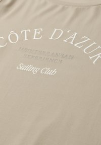 Tela beige con texto en blanco y gris que dice "Côte d'Azur", "Mediterranean Experience" y "Sailing Club" en diferentes tipografías.