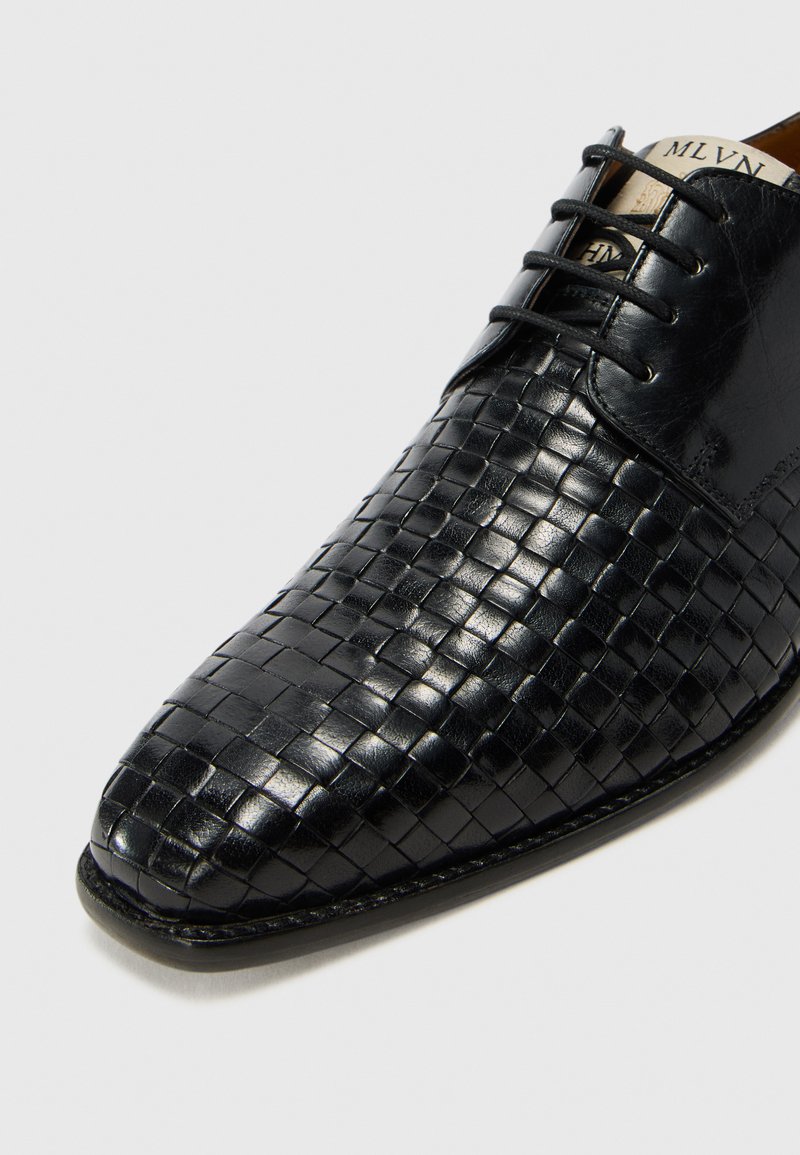 Soulier en cuir noir avec une texture tissée, bout pointu et lacets. Fini lisse avec des accents mats contrastants.