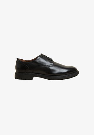 Chaussure en cuir noir avec une texture lisse, bout rond, cinq œillets et une semelle en caoutchouc épaisse avec un motif de traction.