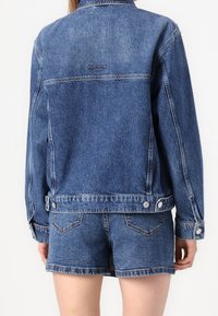 Jeansjacka med en urtvättad look, knappade ärmslut och en märkesetikett på den övre ryggen. Rekommenderas tillsammans med matchande jeansshorts.