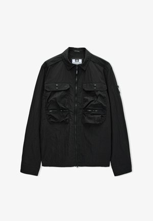 Czarna lekka kurtka z pełnym zamkiem błyskawicznym z przodu, dwoma zapinanymi na guziki kieszeniami na piersi i dwiema dolnymi kieszeniami na zamek, kołnierz złożony w dół.