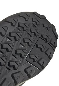 Sort gummisål med dybe, multidirektionale dækmønstre, der har et struktureret design og en fleksibel opbygning for forbedret traction og greb.