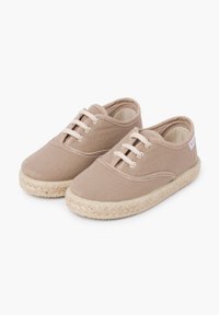 Bež kangas espadrillid sujuva tekstuuriga, ümarate varvastega, kolme silmaga ja punutud jute tallaga. Kui Paris on peen tikandi detail külgedel.