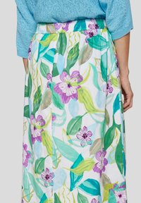 Floral maxi skirt with an elastic waistband, featuring a blend of purple flowers and green leaves on a white background. Lightweight fabric.