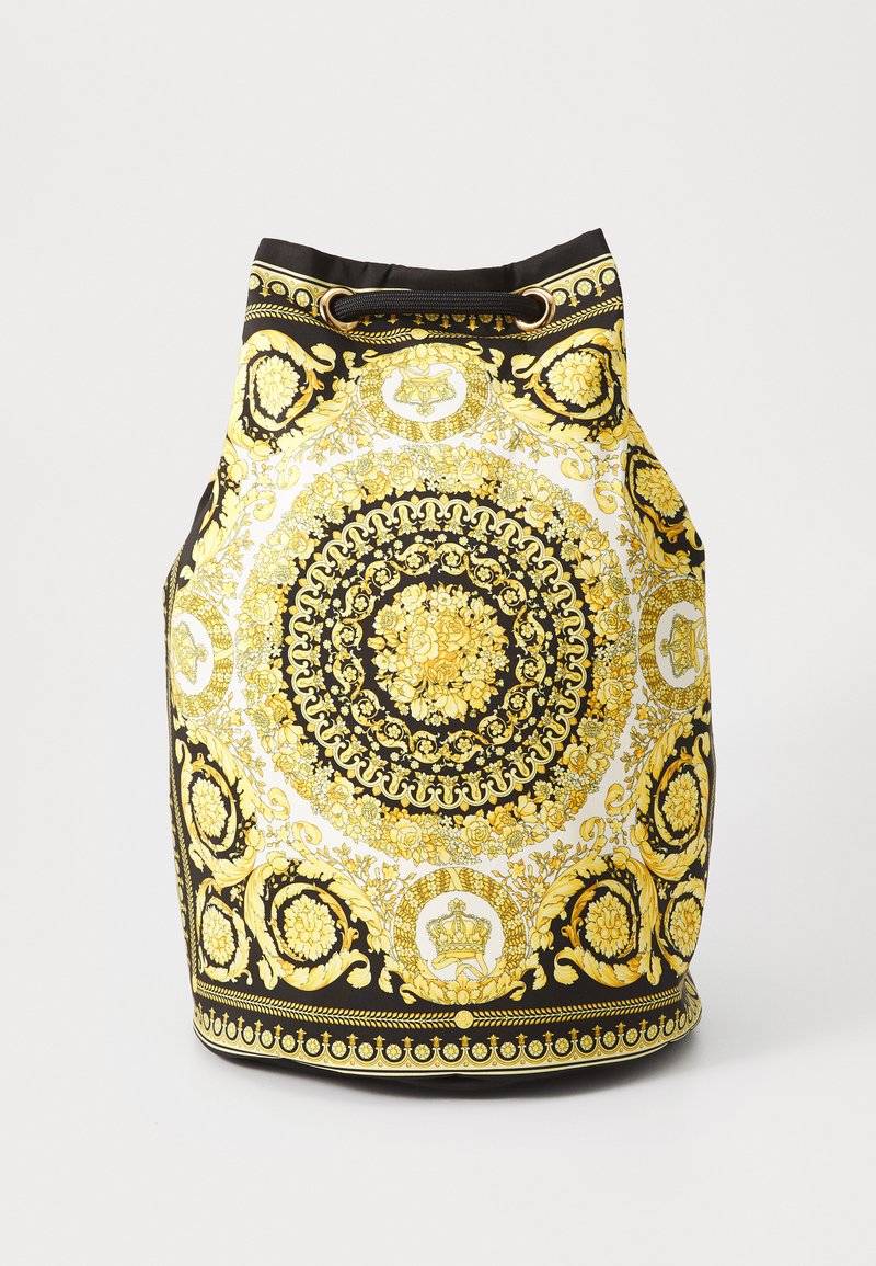 Sac en tissu noir et doré avec un motif floral circulaire, doté d'une ouverture à cordon et d'accents brillants.