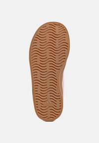 Sole of a sneaker featuring a wavy, textured design in light brown rubber with an embossed logo, positioned against a white background.