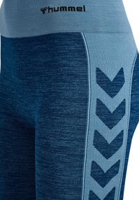 Blaue Leggings aus strukturiertem Material, mit einem einfarbigen dunkelblauen Oberteil, einem hellblauen Bund und gemusterten Akzenten an den Seiten.
