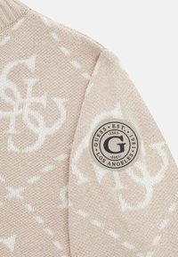 Maglione beige in maglia con motivo logo bianco e un patch circolare del marchio sulla manica, tessuto texturizzato con colletto a coste.