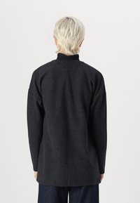 Mörkgrå tröja med hög krage, med en lös passform och långa ärmar, tillverkad av texturiserat tyg, designad för komfort och värme.
