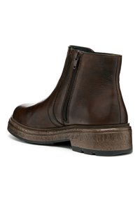 Botín de cuero marrón hasta el tobillo con cremallera lateral, tacón apilado y suela texturada. Presenta un acabado suave y un diseño de punta redonda.