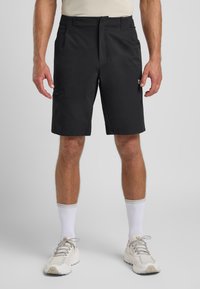 Schwarze Shorts aus leichtem Stoff, mit einem Frontreißverschluss, Seitentaschen und einer einzeln mit Reißverschluss versehenen Tasche am Oberschenkel.