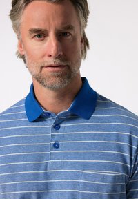 Blå randig polotröja med en enfärgad blå krage, tre blå knappar och fickdetalj. Tyget har en mjuk textur och en avslappnad design.