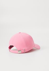 Ροζ καπέλο του μπέιζμπολ με κυρτή γείσο, κατασκευασμένο από ύφασμα. Διαθέτει ρυθμιζόμενο λουράκι πίσω με ασημένια λεπτομέρεια και ετικέτα μάρκας στο εσωτερικό.