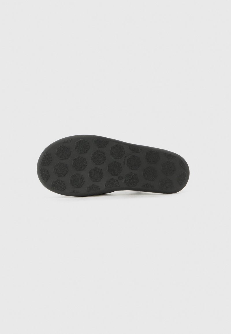 Suela de zapato negra hecha de goma, con un patrón hexagonal texturizado para agarre y tracción. Bordes lisos y diseño de punta redondeada.
