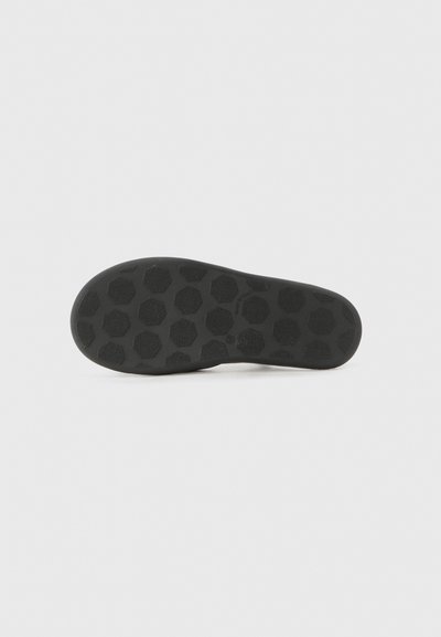 Musta kenkäpidike, joka on valmistettu kumista ja jossa on teksturoitu kuusikulmainen kuvio, joka tarjoaa pitoa ja vetovoimaa. Suorat reunat ja pyöristetty varvasto.