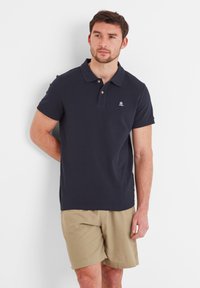 Navy polo shirt made of cotton with a classic collar, short sleeves, and a small logo on the chest, paired with beige shorts.