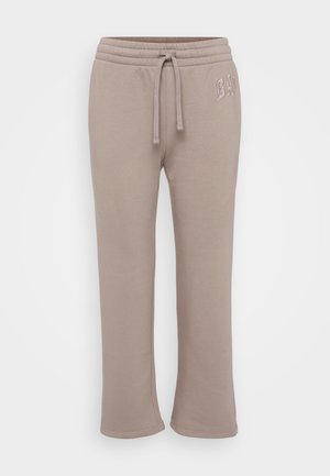 Lyse beige joggebukser laget av myk bomull, med elastisk midje med snøring og en liten brodert logo på siden.