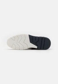 Sko sål med et zigzag mønster. Hvid gummimellemsål med mørkeblå ydersål. Tekstureret for godt greb og stabilitet.