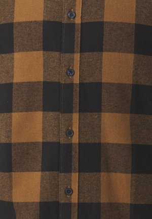 Camisa de franela de cuadros en marrón y negro con botones negros, una tapeta con botones y una textura suave con un patrón de cuadros.