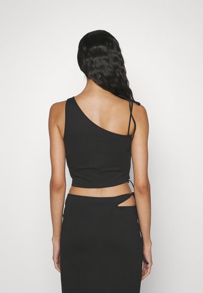 Crop top noir avec un décolleté asymétrique, des bretelles ajustables et une coupe près du corps. Tissu lisse et extensible, associé à une jupe assortie.