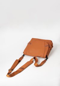 Braune Leder-Umhängetasche mit strukturiertem Finish, verstellbarem Tragegurt und minimalistischer Gestaltung. Sichtbares Fach mit Reißverschluss und Logo-Detail.