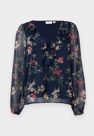 Marineblå, gjennomsiktig bluse med blomstermønster. Har v-hals, volangdetaljer og lange, puffede ermer med elastiske mansjetter.