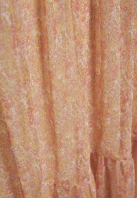 Genomskinlig tyg i ljus persika med rosa och guldfläckar. Mjuk textur med ett svävande mönster och subtila mönster. Lämplig för lager-på-lager-stilar.