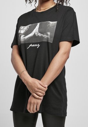 Czarny bawełniany t-shirt z dużym nadrukiem dłoni w pozycji modlitewnej, z białym napisem "pray" pod spodem. Krótkie rękawy, luźny krój.