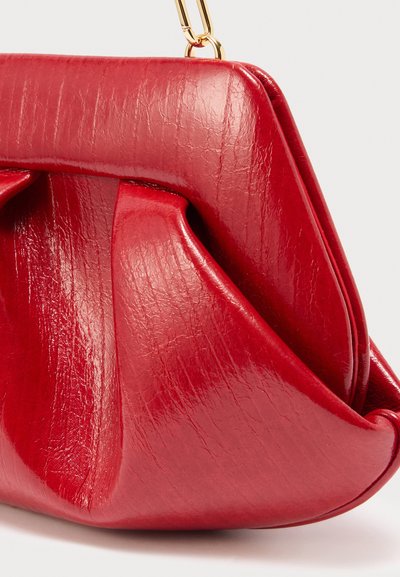 Κόκκινη γυαλιστερή δερμάτινη τσάντα χειρός με σχεδιασμό με πιέτες και χρυσή μεταλλική αλυσίδα για χερούλι, εμφανιζόμενη σε φωτεινό φόντο.