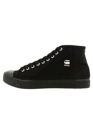 Black high-top canvas sneaker with rubber sole and toe cap, white eyelets, black laces, and "G RAW" logo on the side.