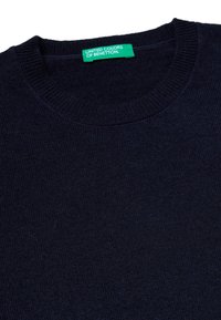 Námořnický modrý pletený svetr s vroubkovaným kulatým výstřihem. Vyroben z měkké tkaniny s etiketou "UNITED COLORS OF BENETTON."