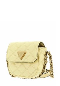 Petite sacoche beige matelassée avec bandoulière chaîne dorée, fermeture à rabat et logo triangulaire Guess à l'avant.