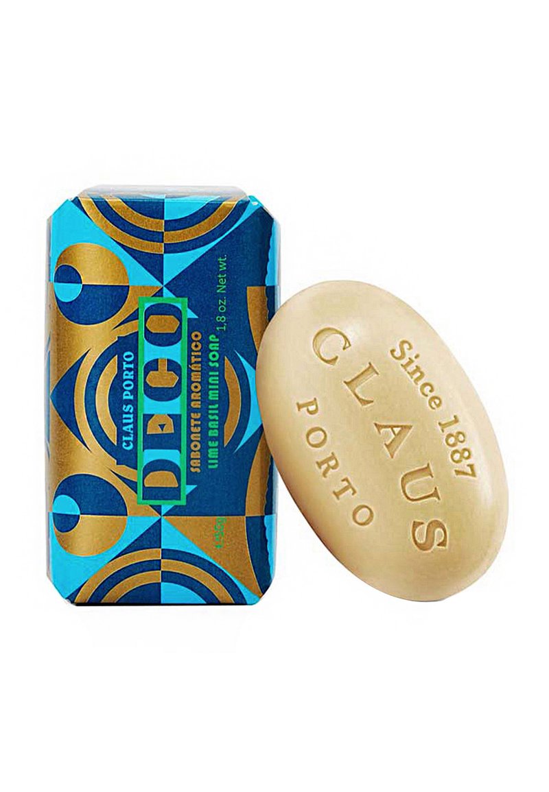 Lime basil soap bar in an off-white color, with CLAUS PORTO embossed. Presented alongside a blue and gold patterned box.