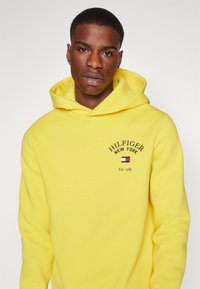 Tommy Hilfiger ARCHED VARSITY HOODY - Sportinis megztinis - eureka yellow