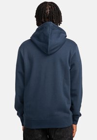 Marineblaue Kapuzenjacke aus weicher Baumwolle, mit großer Kapuze und gerippten Bündchen und Saum. Minimalistisches Design ohne sichtbare Logos oder Muster.