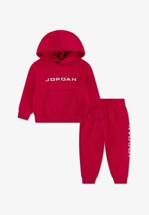 Crvena dukserica s kapuljačom i prednjim džepom, bijelog "JORDAN" logotipa, u kombinaciji s odgovarajućim trenirkom koji ima logotip uz vanjsku stranu nogavice.